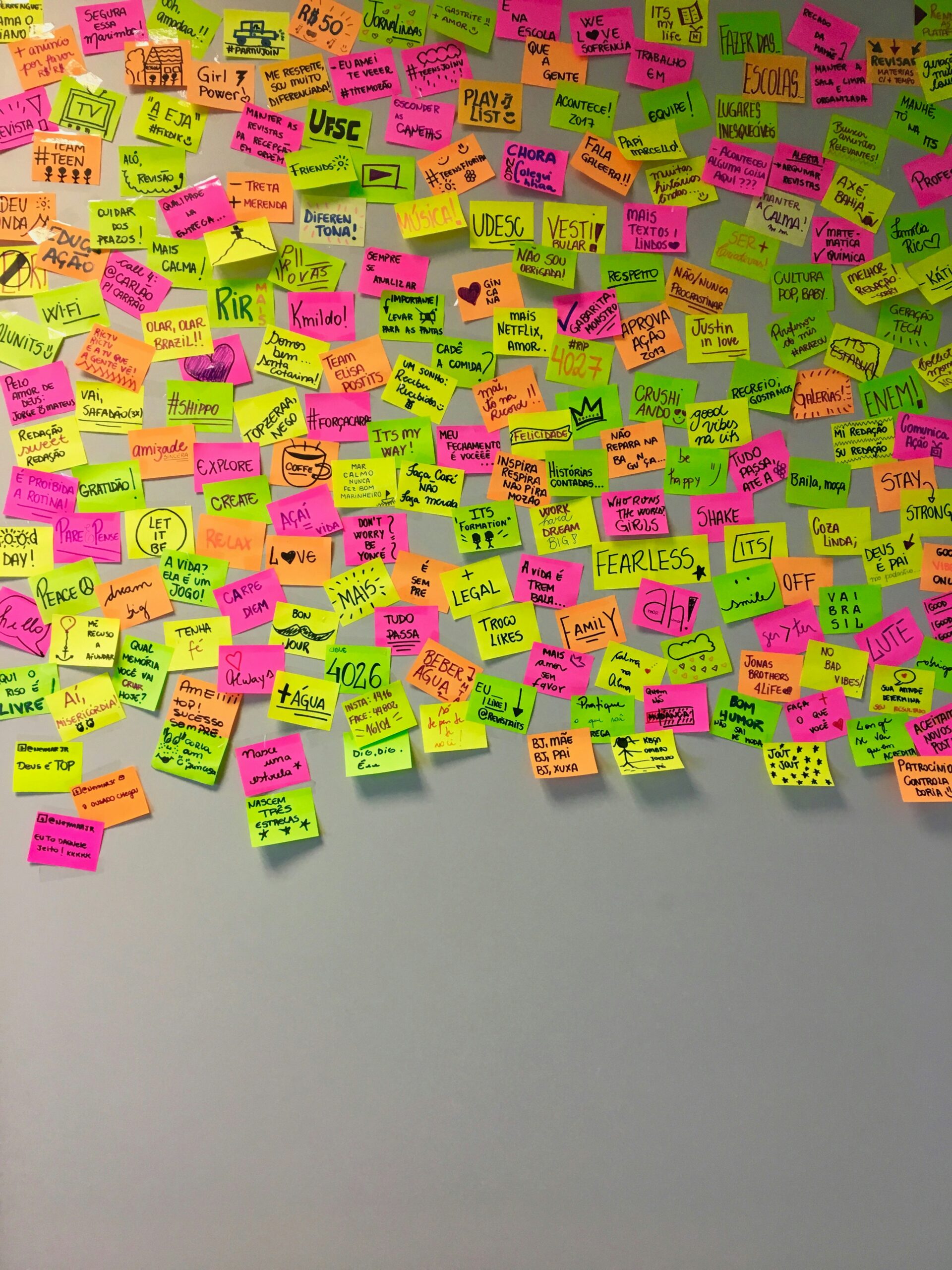 A wall full of post-its in different colors, with diverse work-related terms written on them